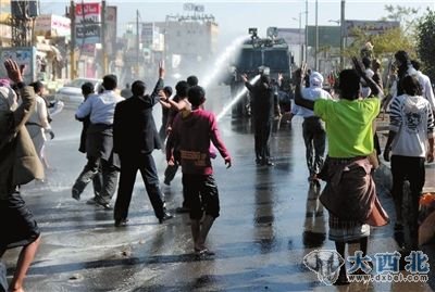 12月24日，也门首都萨那，抗议示威者游行遭到高压水枪驱散。新华社发
