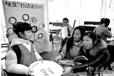 昨天,在一家餐厅内一名小朋友倡导用餐客人在一只“巨型光盘”上签名留言,加入到“光盘行动”中。新华社发