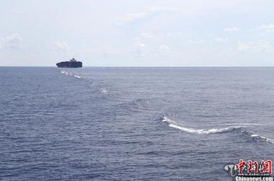 经过连续90多小时破浪前行,海南赴南沙捕捞船队于10日上午10时许穿过北纬12度线,进入南沙海区航行。南沙群岛扼控太平洋与印度洋的海上交通线,记者上午不时看到有大型集装箱船从船队不远处驶过。图为一艘大型集装箱船朝东北方向驶去。轮船驶过带起的海浪延绵数公里。王子谦摄